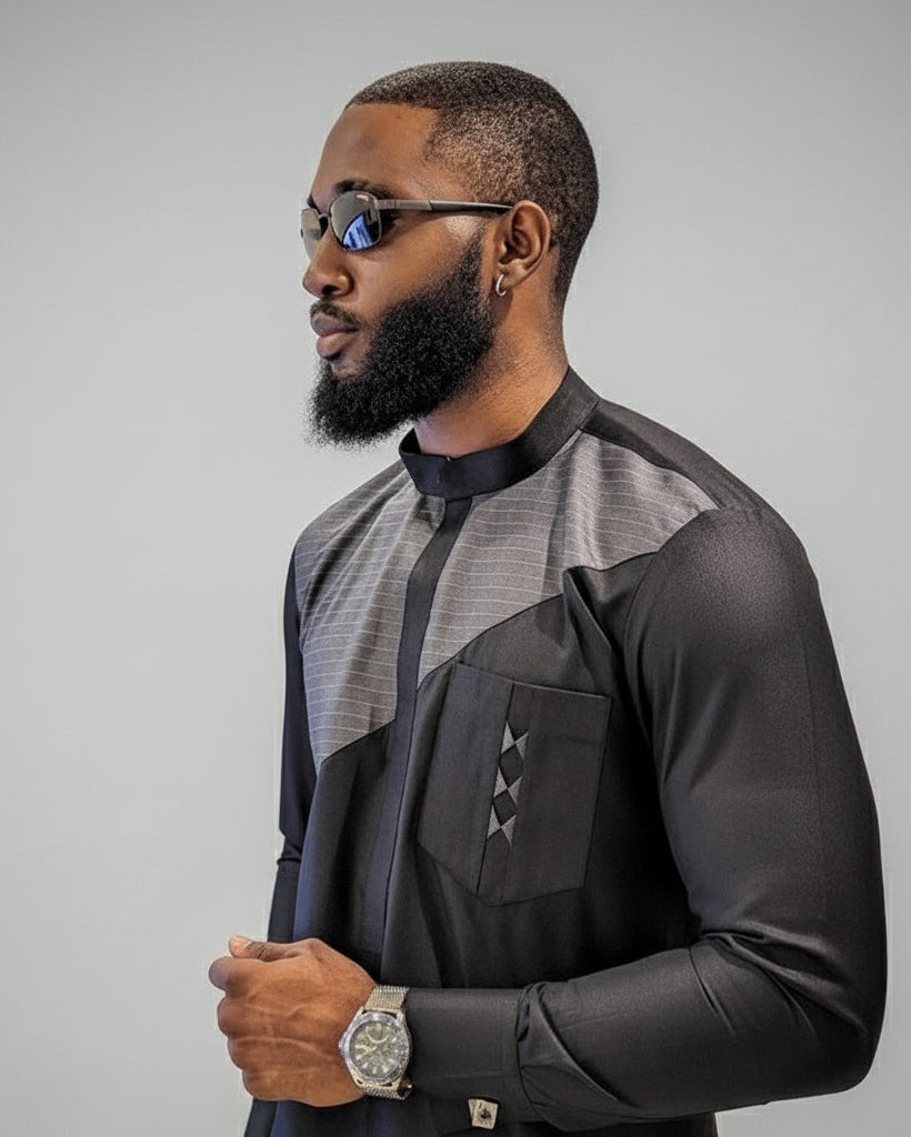 Man wearing a stylish black and gray outfit with sunglasses on a gray background