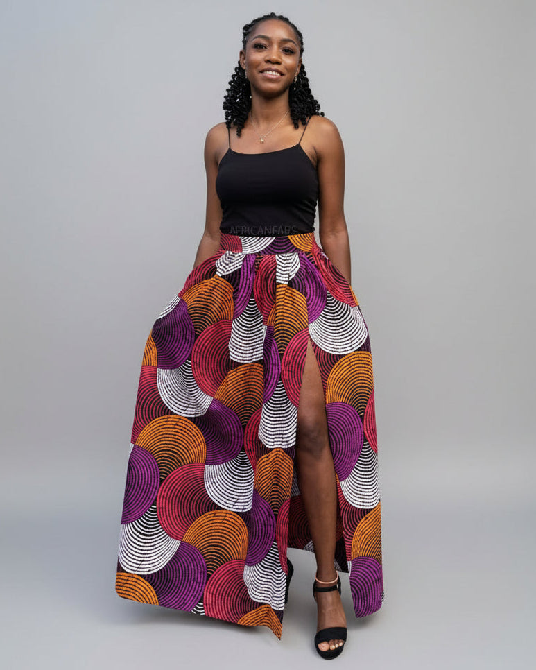 Woman wearing a colorful patterned skirt with a black top on a gray background