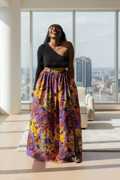 Woman in a colorful dress standing in a room with large windows overlooking a cityscape.