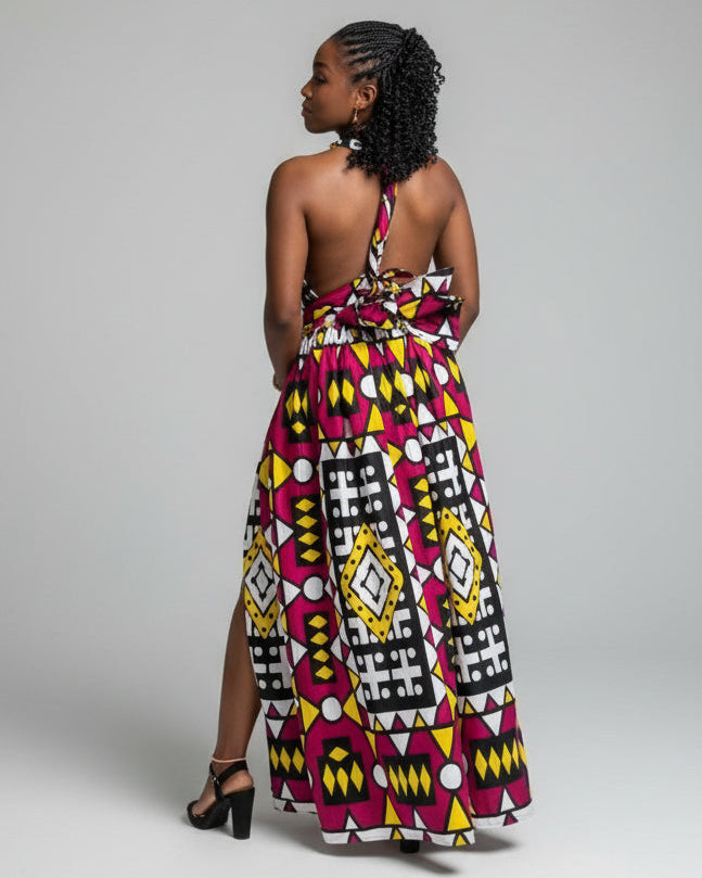Woman wearing a colorful patterned dress standing outdoors with greenery in the background