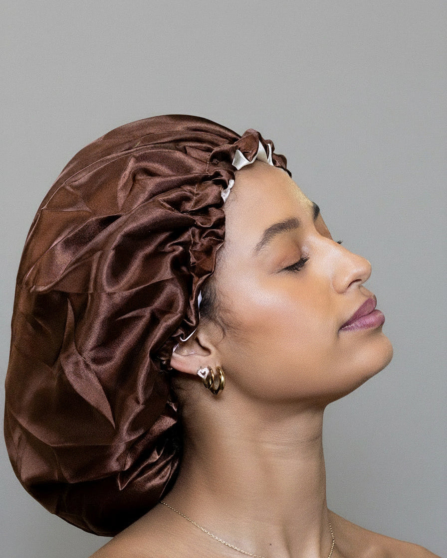 Woman wearing a brown satin bonnet against grey background