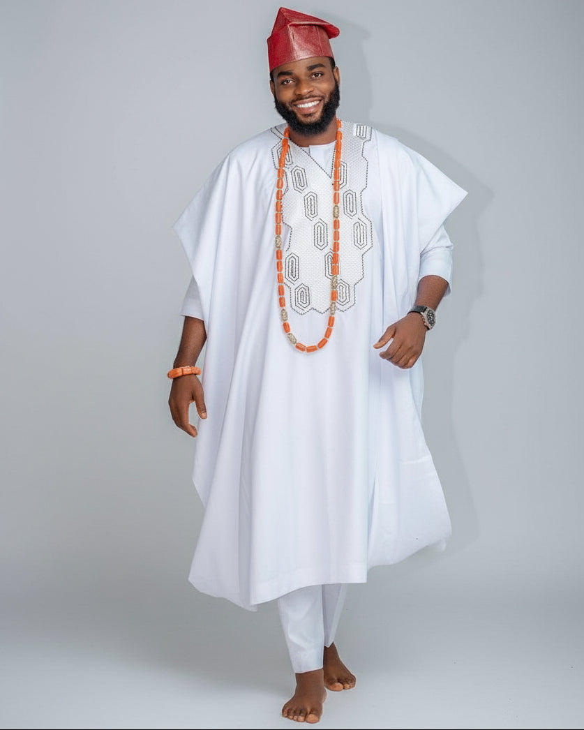 Man wearing traditional white outfit with red cap on a gray background